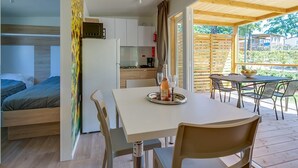Una habitación compacta y moderna con cama, kitchenette y zona de comedor con mesa y sillas.