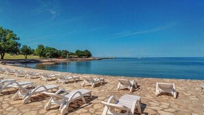 Un área frente a la playa con tumbonas y una vista despejada del mar.