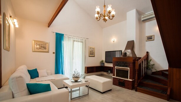 Ein modernes Wohnzimmer mit einem weißen Sofa, einem Couchtisch, einem Kamin und einer Treppe.