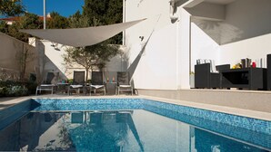 Ein Schwimmbad mit Liegestühlen und einem schattigen Bereich.