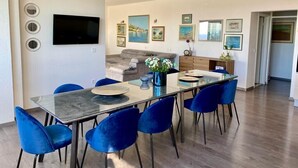 A modern dining area with a glass table, blue chairs, a chandelier, and artwork on the walls. - Villa Noura in Makarska, private pool,gym (Makarska)