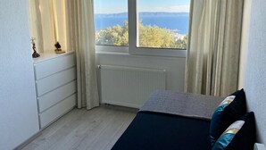A bedroom with a view of the sea, a radiator, a dresser, and a bed with pillows. - Villa Noura in Makarska, private pool,gym (Makarska)