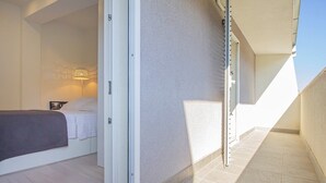 A bedroom with a bed, a nightstand, and a wall-mounted lamp.