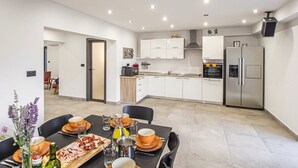 A modern kitchen with white cabinets, stainless steel appliances, and a dining area with a table set for four.