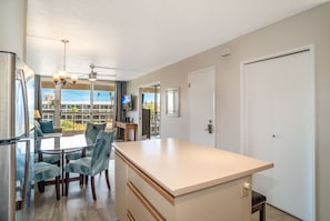A modern kitchen with a central island, dining area with chairs, and a view of the outdoors.