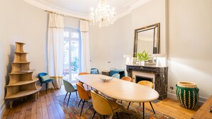 A dining area with a wooden table, chairs, a chandelier, a fireplace, and a large mirror. - Suite MASSAI MARA ideal for 4 people (Bordeaux)