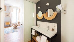 A modern bathroom with a black accent wall, two round mirrors, a white sink, and a towel rack. - Suite MASSAI MARA ideal for 4 people (Bordeaux)