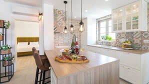 Une cuisine moderne dotée d’un îlot central, de luminaires suspendus et d’un bar pour prendre le petit-déjeuner.