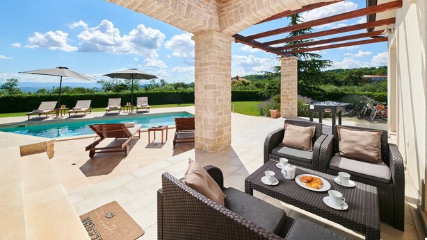 A poolside area with lounge chairs, a table with cups and a plate, and a pergola structure. - Modern Villa Melli with a pool, Whirlpool and panoramic View (Vizinada)