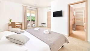 A bedroom with a bed, a desk, a chair, a TV, and a bathroom with a shower and toilet. - Modern Villa Melli with a pool, Whirlpool and panoramic View (Vizinada)