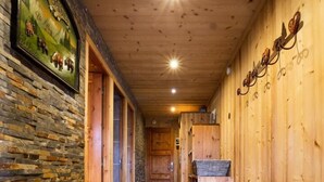A wooden hallway with a stone wall on one side, a bench, and a sign on the wall.