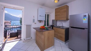 Eine kompakte Küche mit Kücheninsel aus Holz, einem Samsung-Kühlschrank und Meerblick durch eine offene Tür.