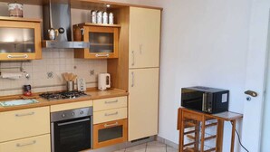 A compact kitchen with a gas stove, oven, microwave, and wooden cabinets. - 1 Bed Flat - Sleeps 2 - Parking - Wifi (San Biagio della Cima)