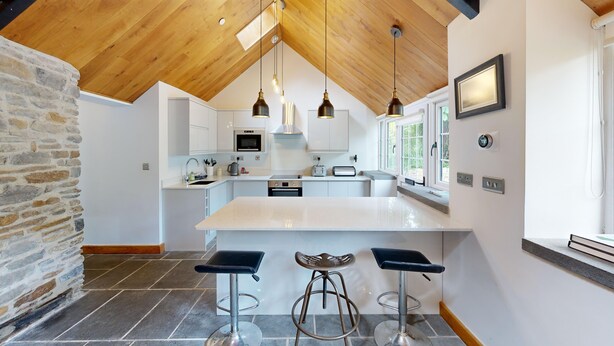 Una cocina moderna con una isla central, taburetes de bar e iluminación colgante.