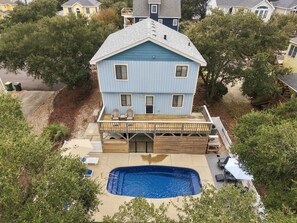 Ein zweistöckiges Haus mit einer Veranda, einem Swimmingpool und einer überdachten Terrasse.