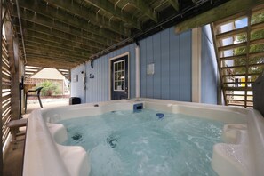 Ein Whirlpool unter einer Holzw pergola mit Blick auf ein Haus und einen Garten.