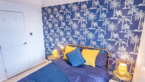 A bedroom with a bed, a nightstand, a lamp, and a door. - Perfect flat for the beach and town centre (Bournemouth)
