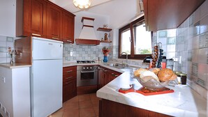 Una cocina con armarios de madera, un refrigerador blanco, una estufa y un ventanal.