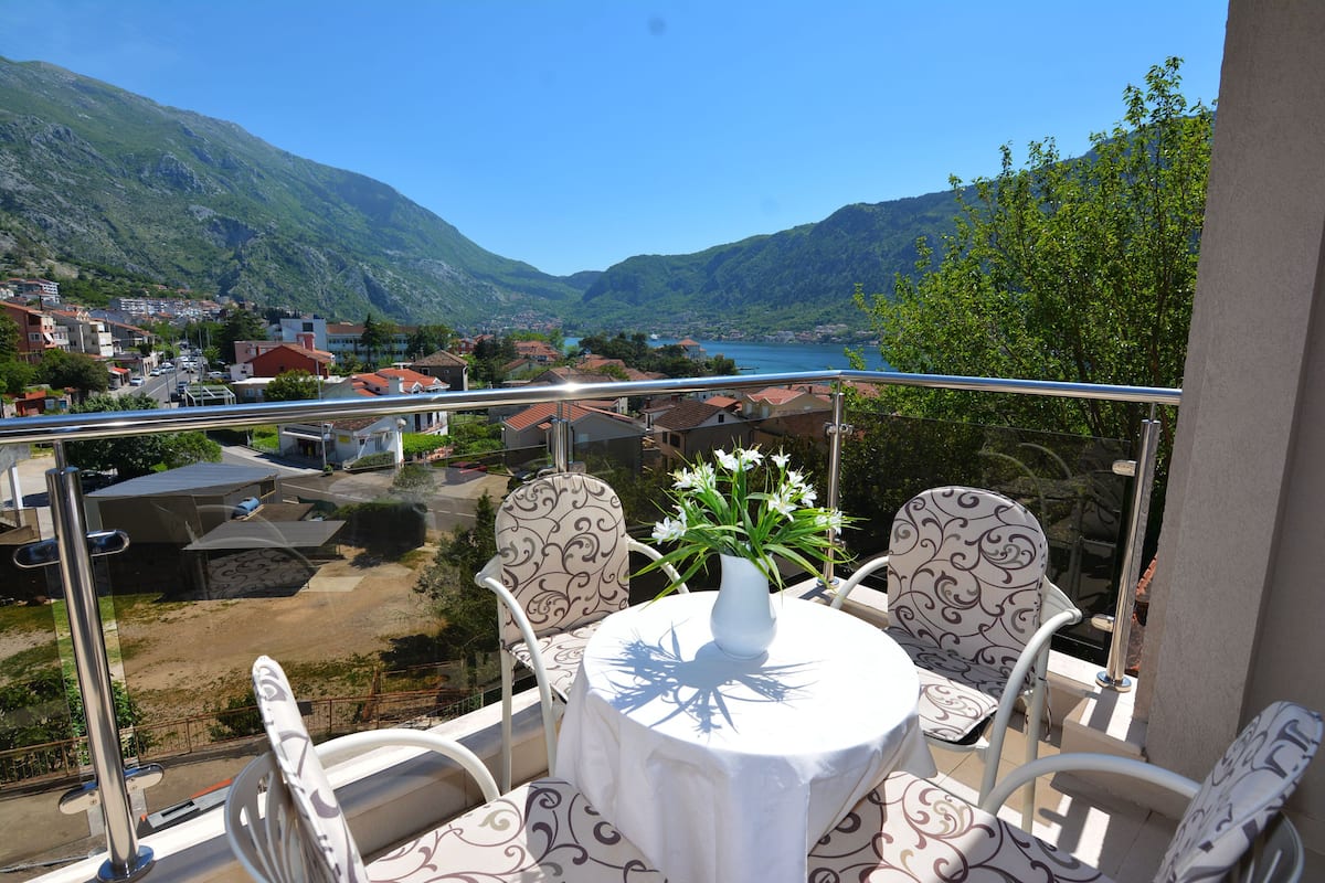 Ein Balkon mit Tisch und Stühlen mit Blick auf eine Berglandschaft und ein Gewässer.