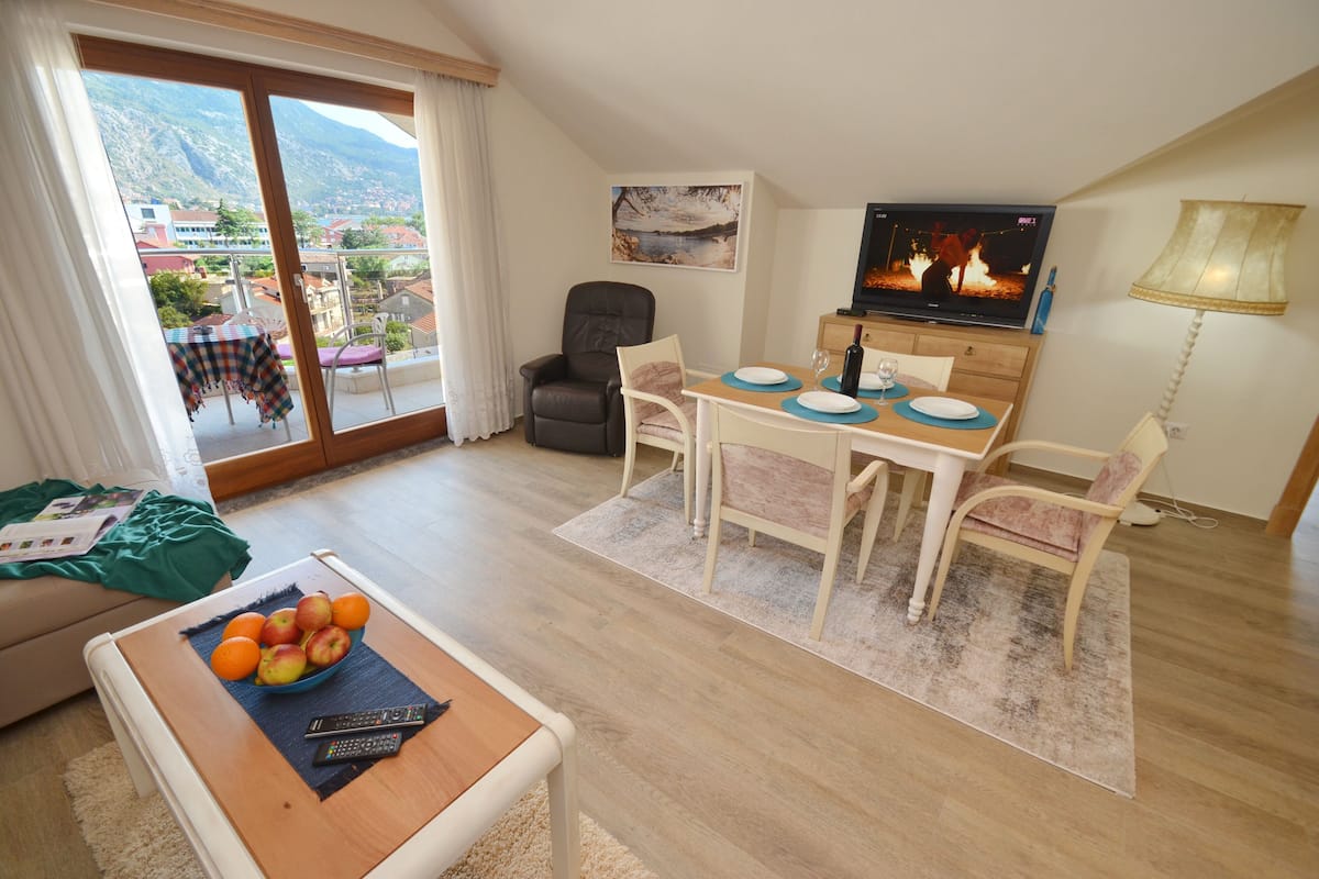 Ein Wohnzimmer mit Essbereich, Fernseher und Bergblick.