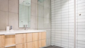 A modern bathroom with a wooden vanity, a large mirror, and a tiled shower area. - Modern 1 Bedroom Apartment in Century City (Cape Town)