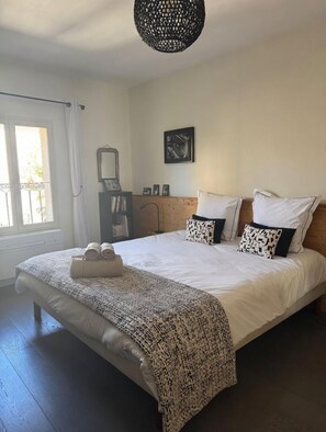 Een slaapkamer met een groot bed, een nachtkastje, een spiegel en een lijst met een foto aan de muur.