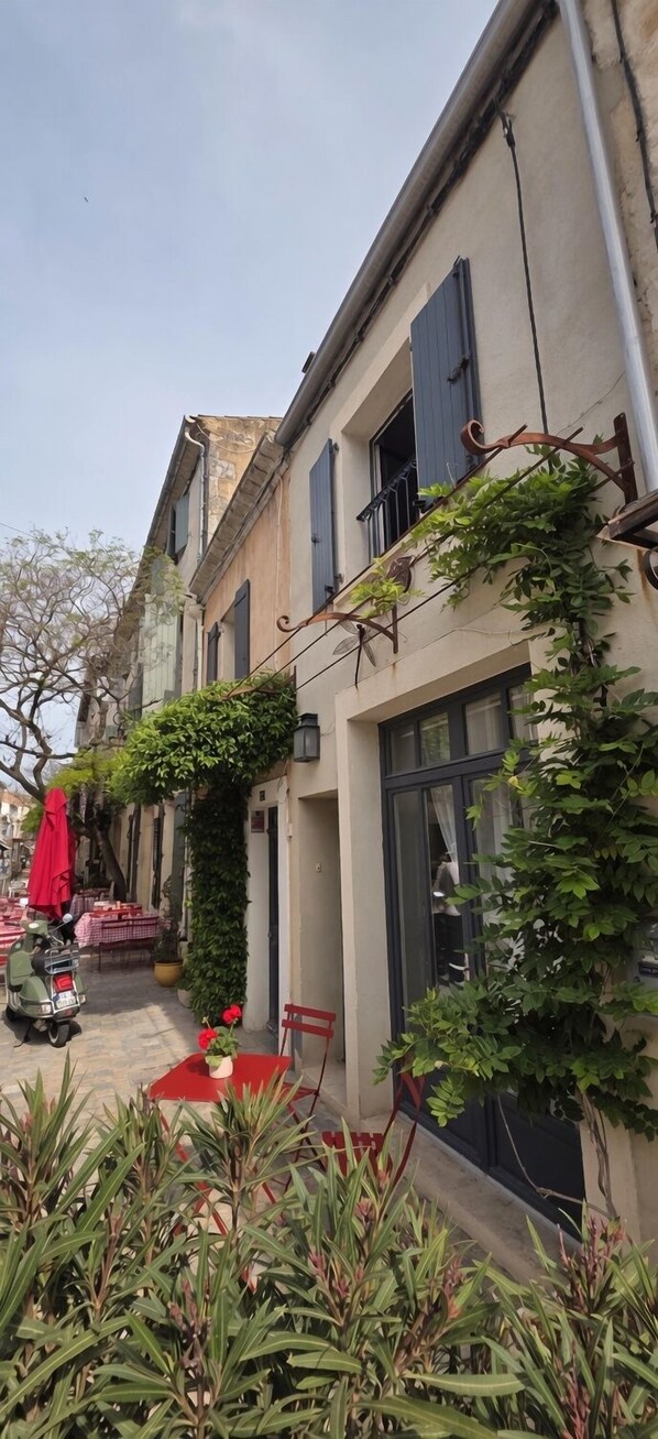 A courtyard with a scooter, outdoor seating, and a red umbrella.