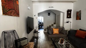 Een ruime woonkamer met een hoge nok, een houten salontafel, een bank en een televisie.
