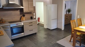 A modern kitchen with a built-in oven, a refrigerator, and wooden cabinets. - Kaiserstuhl "auszeit " (Vogtsburg im Kaiserstuhl)