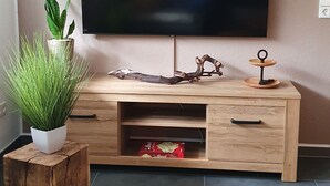 A wooden TV stand with a flat-screen TV, a potted plant, and a decorative item on top. - Kaiserstuhl "auszeit " (Vogtsburg im Kaiserstuhl)