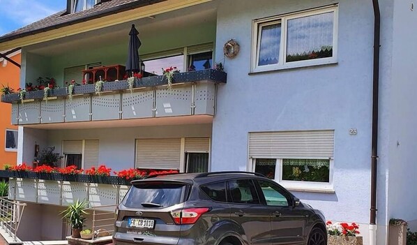 A multi-story residential building with balconies adorned with potted plants and flowers.