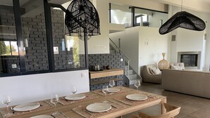 A modern dining area with a long wooden table set for four, surrounded by wooden chairs. - Golfe de Saint-tropez, Villa Contemporaine Avec Piscine, vue mer et Plage à Pied (Cavalaire-sur-Mer)
