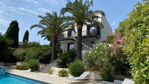 A modern building with a pool, palm trees, and a staircase leading to a balcony. - Golfe de Saint-tropez, Villa Contemporaine Avec Piscine, vue mer et Plage à Pied (Cavalaire-sur-Mer)