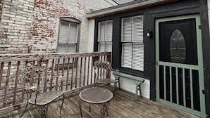 A rustic building with a wooden deck, a black door with a green frame, and a small window. -  Stay downtown within walking distance of restaurants, shopping, and breweries! (Bardstown)
