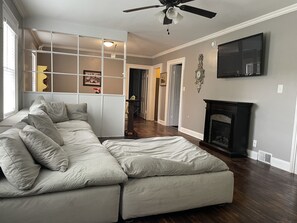 A living room with a sectional sofa, a fireplace, and a television mounted on the wall. -  Stay downtown within walking distance of restaurants, shopping, and breweries! (Bardstown)