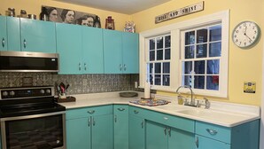 A kitchen with teal cabinets, a black and white checkered floor, a microwave, an oven, a sink, and a clock. -  Stay downtown within walking distance of restaurants, shopping, and breweries! (Bardstown)