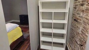 A narrow room with a wooden floor, a white shelving unit, and a brick wall. -  Stay downtown within walking distance of restaurants, shopping, and breweries! (Bardstown)