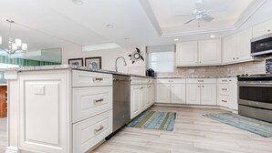 Una cocina moderna con armarios blancos, horno empotrado y ventilador de techo.