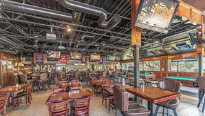 A restaurant with multiple tables and chairs, a pool table, and various signs and posters on the walls. - Folly Field Villa : Steps to Beach · Private Decks · Pool · Bikes, Golf & Dolphin Tour Included (Hilton Head Island)