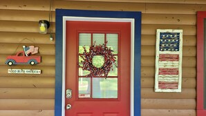 A red door with a wreath, a small American flag, and a 'God Bless America' sign. - The Patriot Cabin close to the Buffalo National Park and River! Sleeps 4! (Harriet)