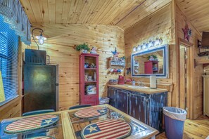 A wooden cabin interior with a dining area, a kitchen with a sink, and a mirror above the counter.