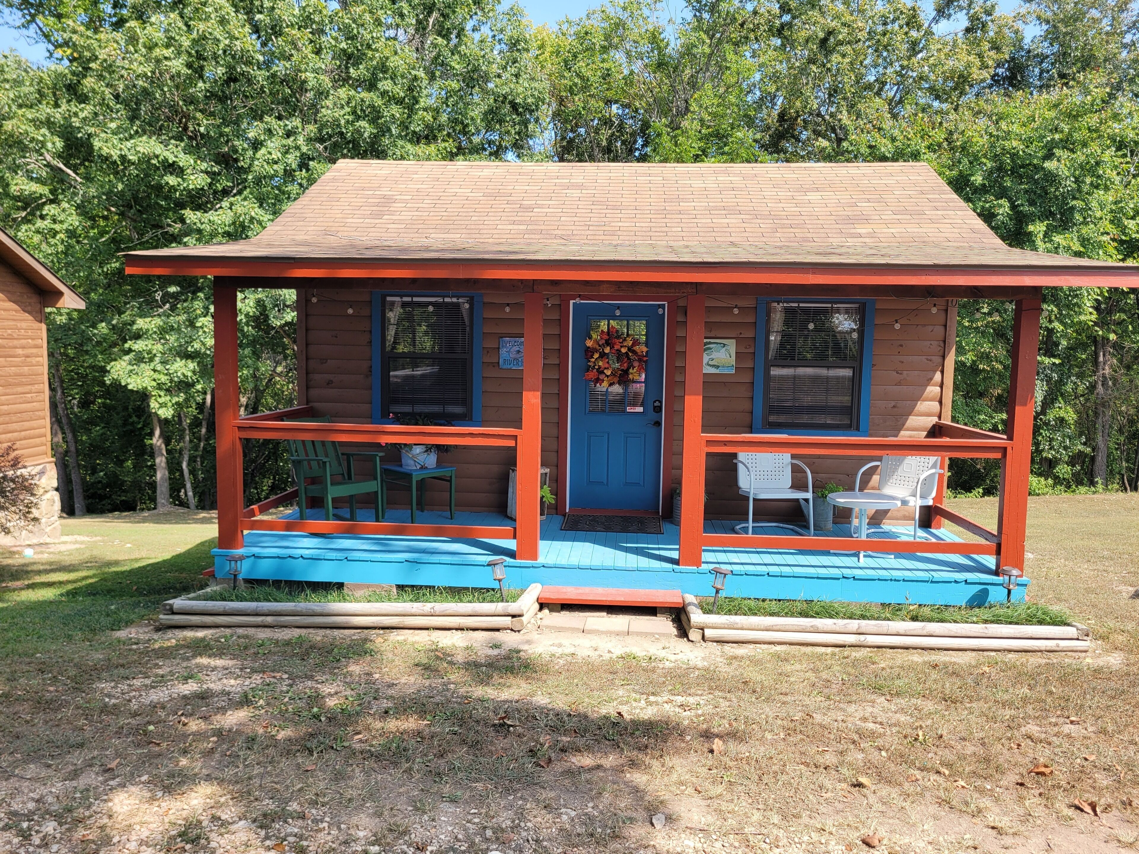 A small cabin with a porch, two windows, and a door.