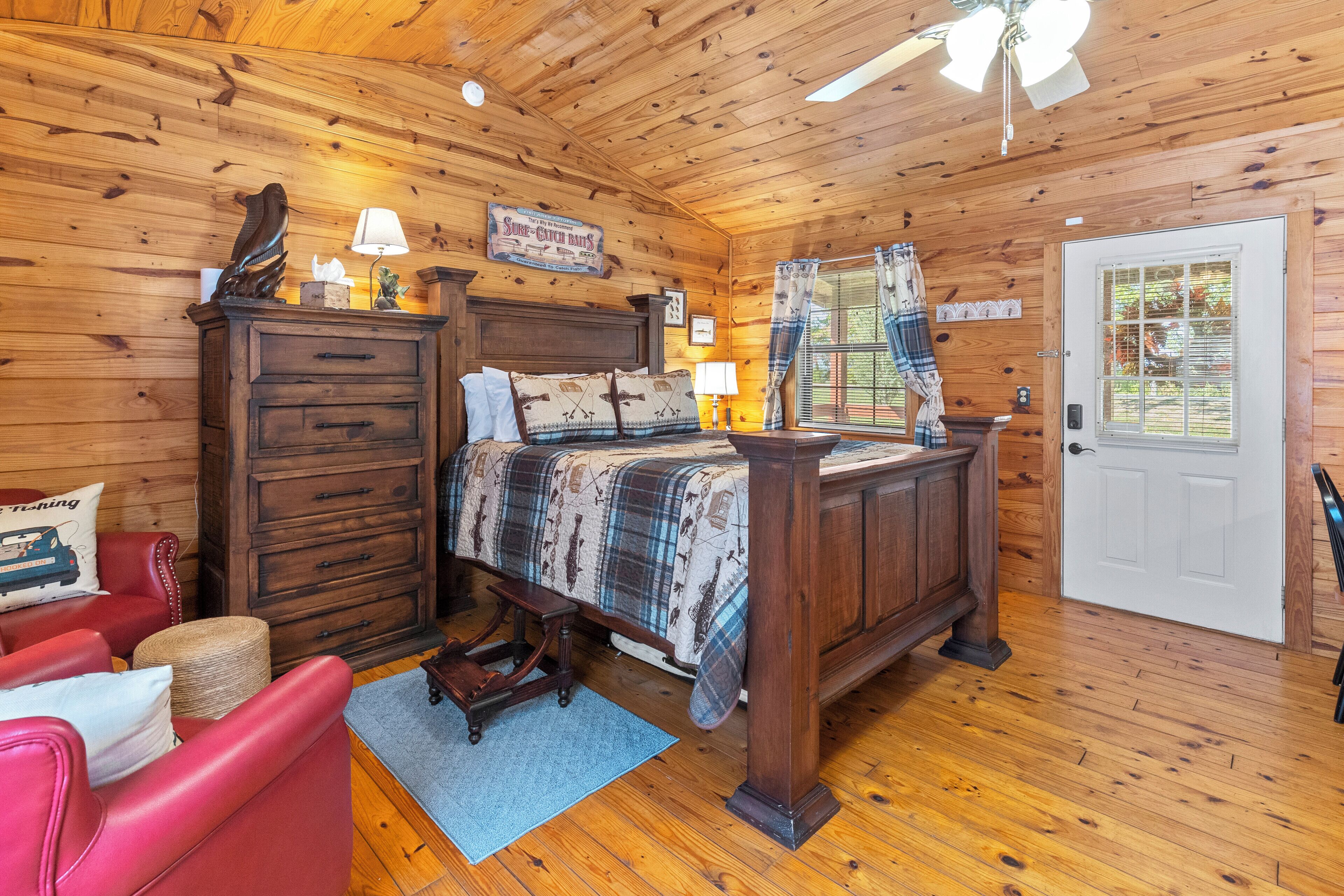 A wooden-paneled bedroom with a bed, dresser, and a red chair.