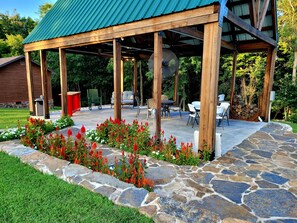 A covered patio area with stone flooring, wooden pillars, and outdoor furniture.