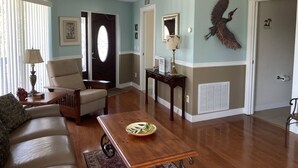 A living room with a sofa, coffee table, and a decorative bird on the wall.