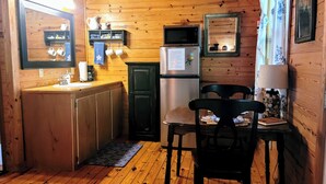 A wooden cabin interior with a kitchen area featuring a refrigerator, microwave, and wooden cabinets.