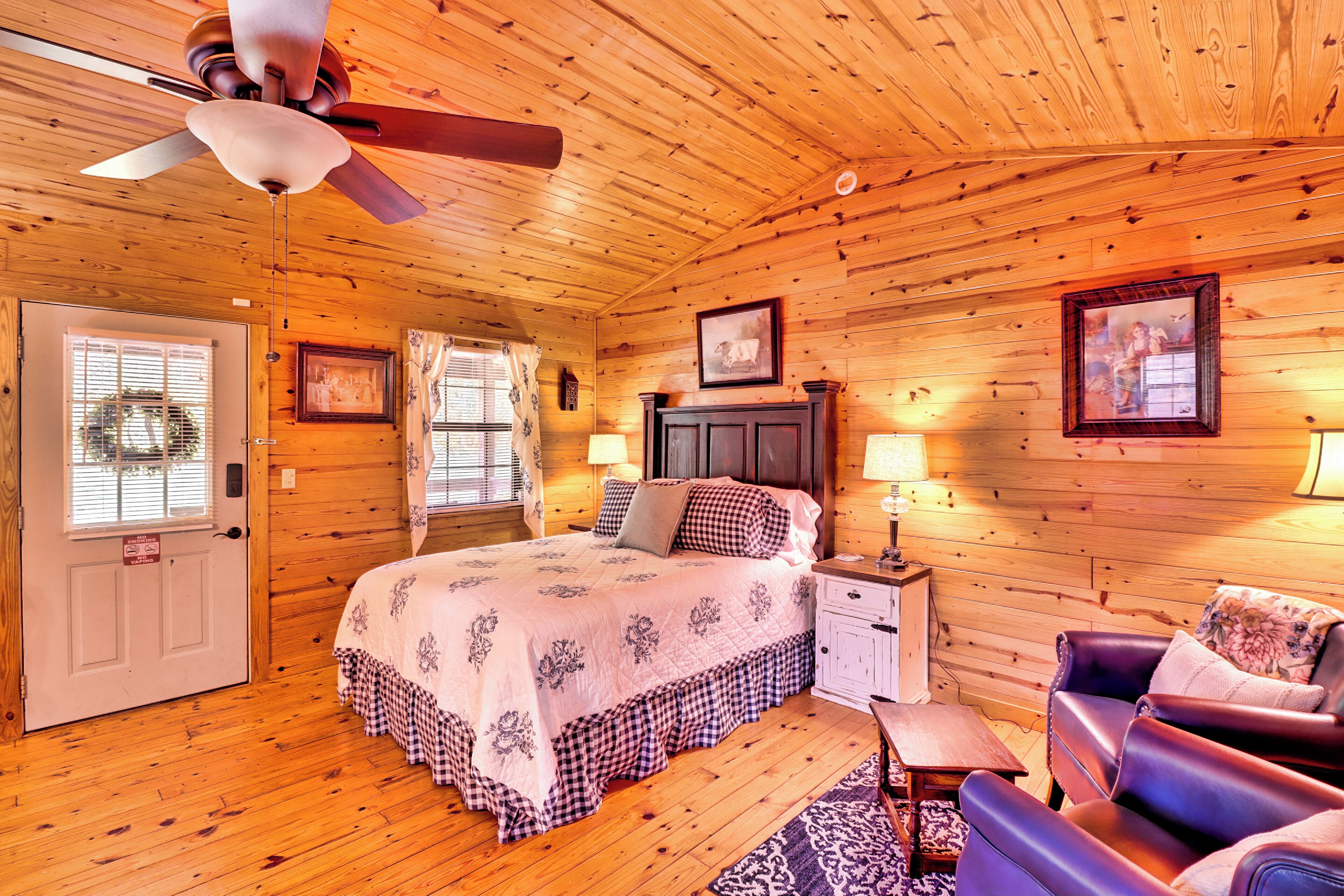 A wooden cabin bedroom with a bed, a nightstand, a chair, and a ceiling fan.