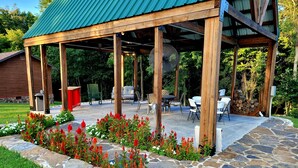 Un patio techado con suelo de piedra, pilares de madera y mobiliario exterior.