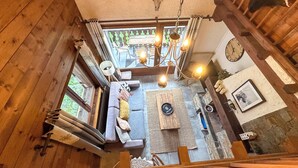 A rustic cabin interior with a loft bed, a sofa, a dining table, and a chandelier. - Charming 3 Bedroom Alpine Apartment. Central location and with beautiful views (Samoëns)