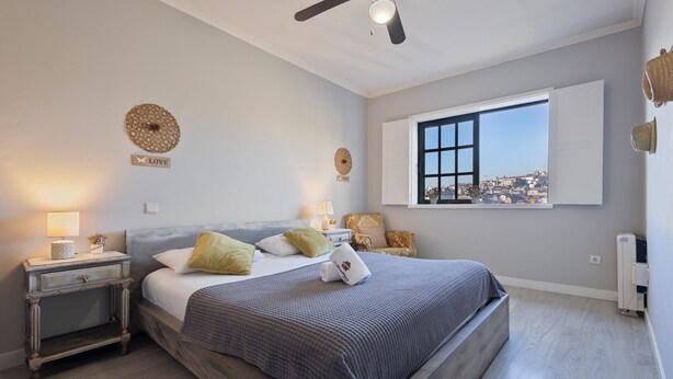 A bedroom with a bed, nightstands, a window with a view, and decorative wall art. - MyRiverPlace N.5 - PORTO Riverfront Apartment With Breathtaking Views (Vila Nova de Gaia)
